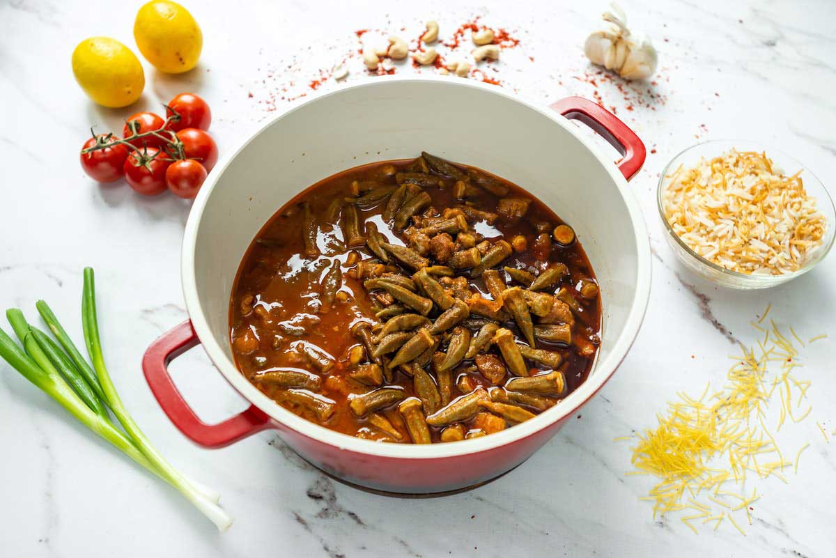 Okra Draufsicht auf einen herzhaften Okra-Eintopf mit Reis und frischen Zutaten auf einem hellen Tisch.